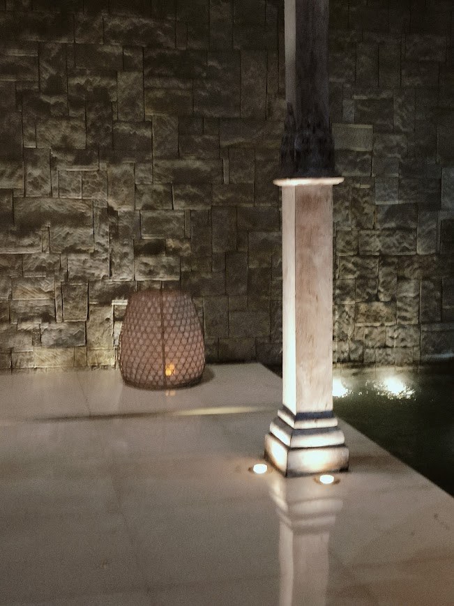 Stone wall with marble pedestal and lantern at night